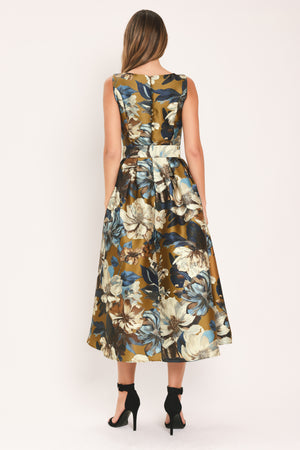 A woman modeling a sleeveless midi dress with a floral print in olive green, navy blue, beige, and white | Flying Tomato