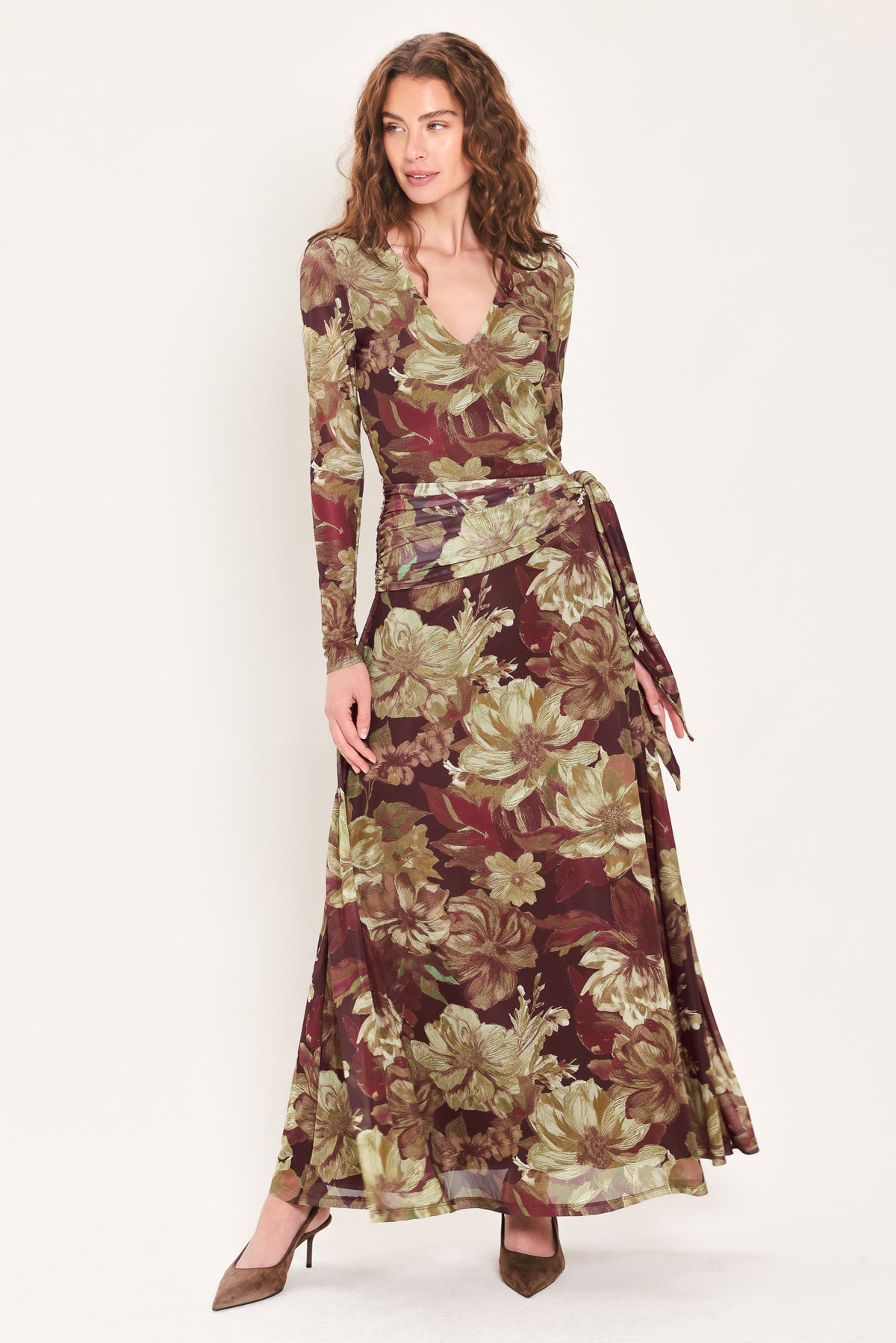 Woman wearing a dark maroon long sleeve mesh maxi dress with brown floral pattern and a waist tie belt that sits right above the hip | Flying Tomato