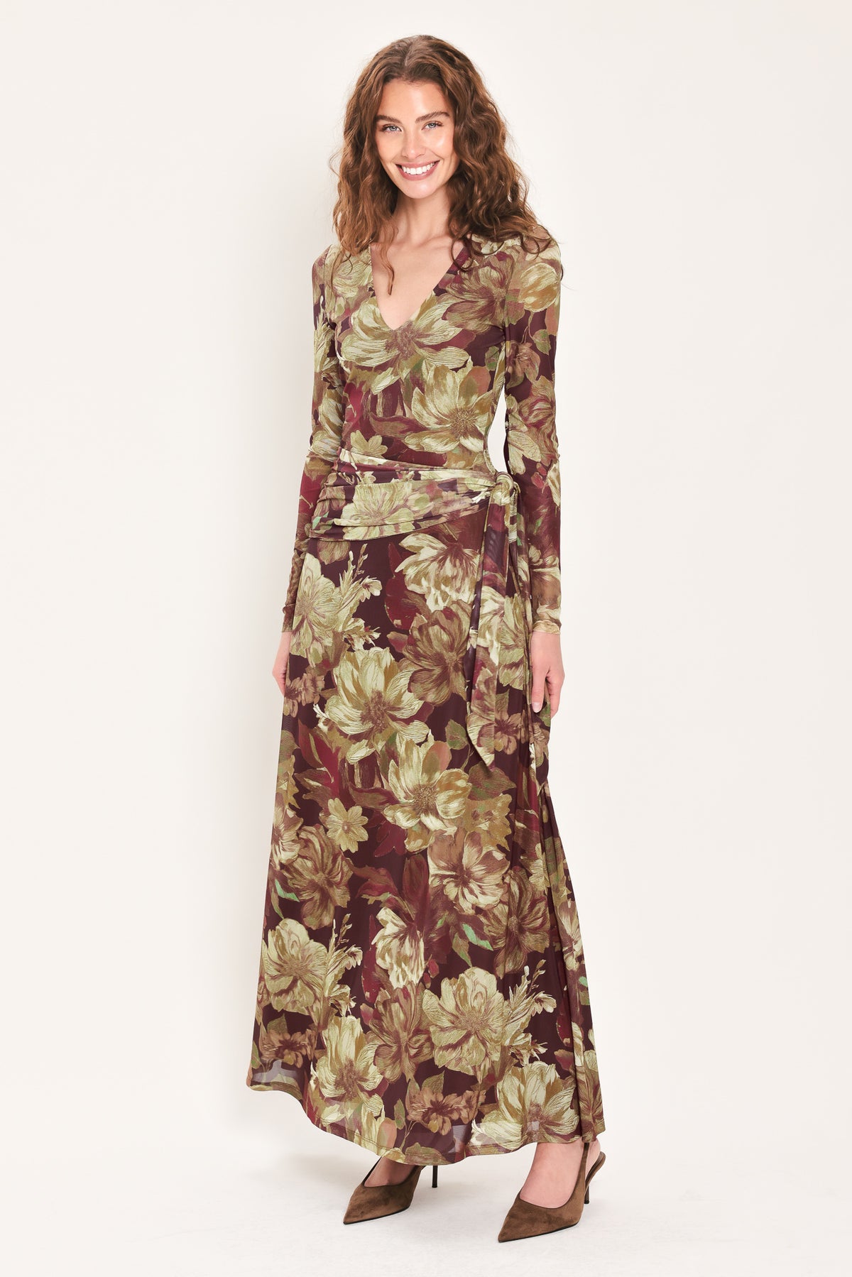Woman wearing a dark maroon long sleeve mesh maxi dress with brown floral pattern and a waist tie belt that sits right above the hip | Flying Tomato