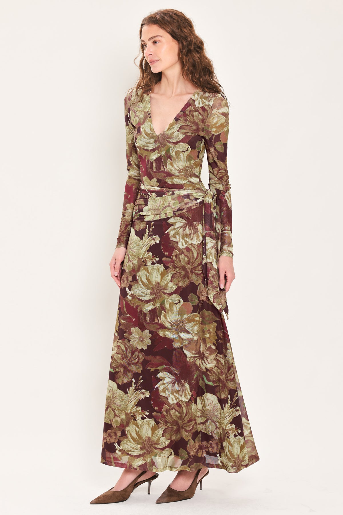 Woman wearing a dark maroon long sleeve mesh maxi dress with brown floral pattern and a waist tie belt that sits right above the hip | Flying Tomato