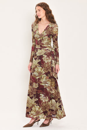 Woman wearing a dark maroon long sleeve mesh maxi dress with brown floral pattern and a waist tie belt that sits right above the hip | Flying Tomato