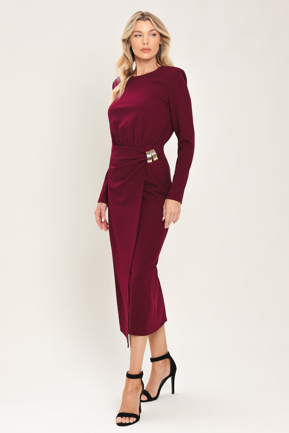 Woman wearing a long sleeve burgundy midi dress with a gold hardware holding slight gathered detailing around the hip | Flying Tomato
