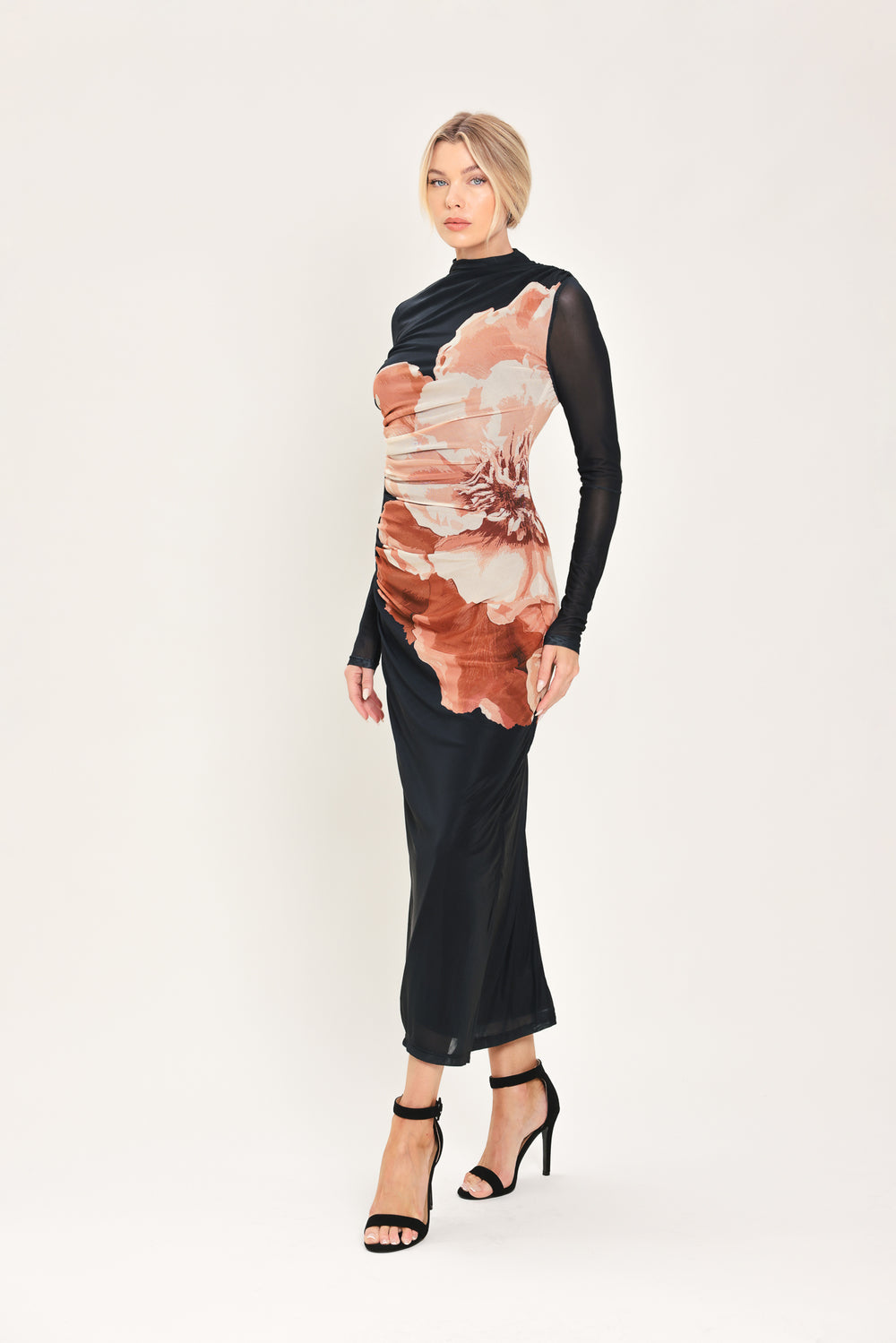 A woman modeling a black long-sleeve mock-neck mesh midi dress with a large abstract floral print in brown, beige, and white on the front | Flying Tomato