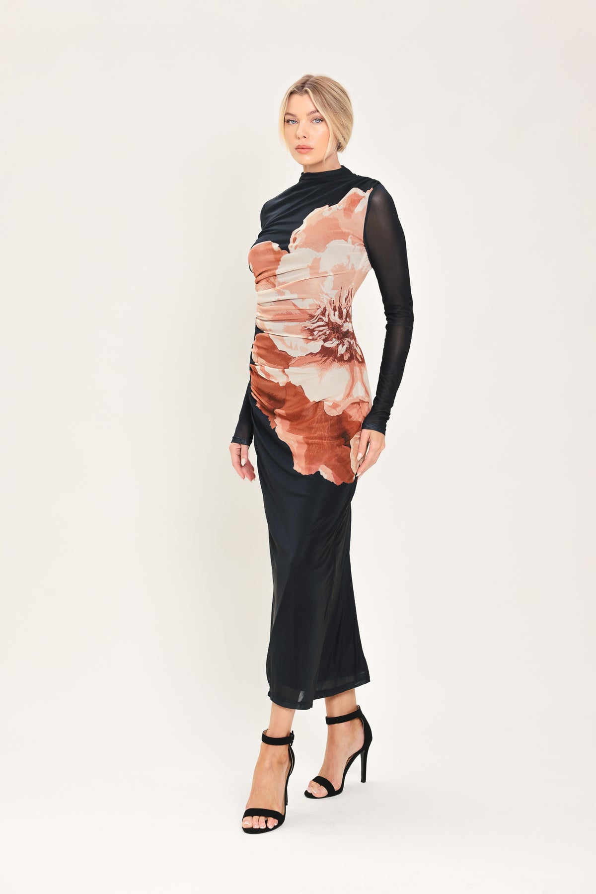 A woman modeling a black long-sleeve mock-neck mesh midi dress with a large abstract floral print in brown, beige, and white on the front | Flying Tomato