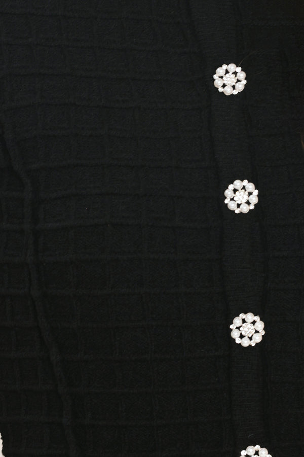 A woman modeling a black textured cropped cardigan with decorative silver buttons down the front | Flying Tomato