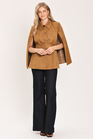 Woman wearing a camel suede capelet jacket with a collar, buttons, and matching  waist belt | Flying Tomato