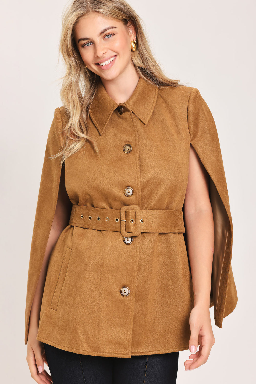 Woman wearing a camel suede capelet jacket with a collar, buttons, and matching  waist belt | Flying Tomato