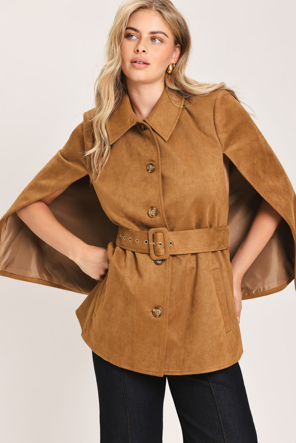 Woman wearing a camel suede capelet jacket with a collar, buttons, and matching  waist belt | Flying Tomato