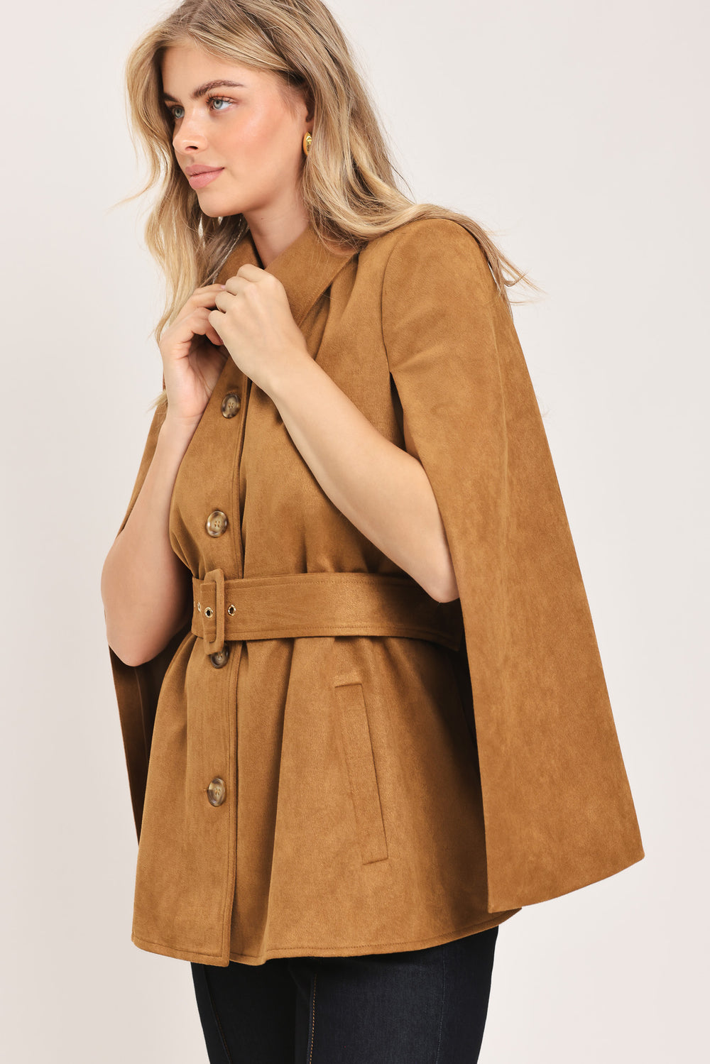 Woman wearing a camel suede capelet jacket with a collar, buttons, and matching  waist belt | Flying Tomato
