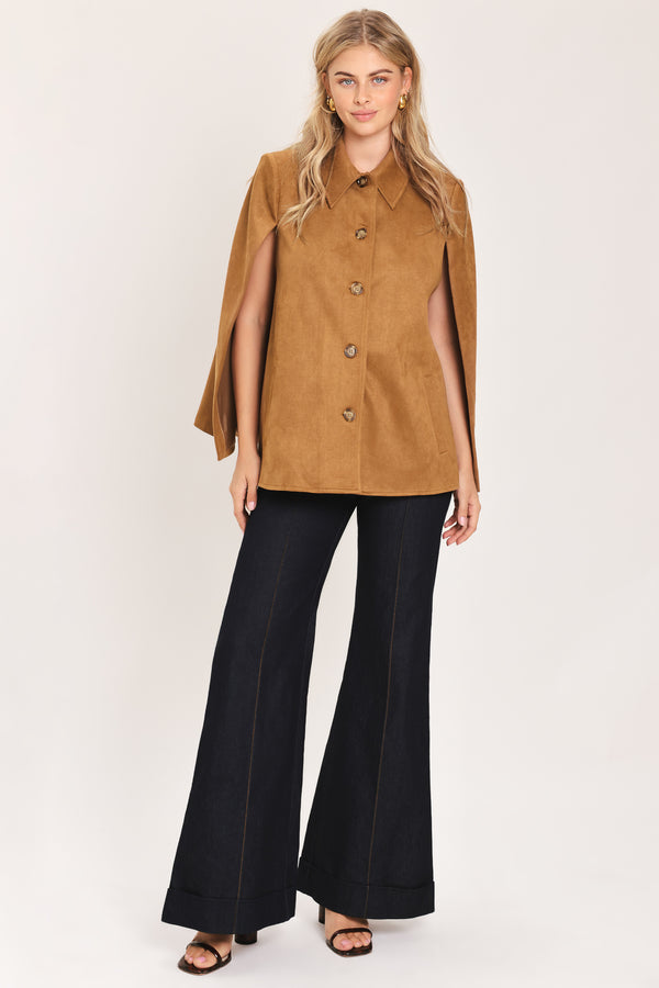 Woman wearing a camel suede capelet jacket with a collar, buttons, and matching  waist belt | Flying Tomato