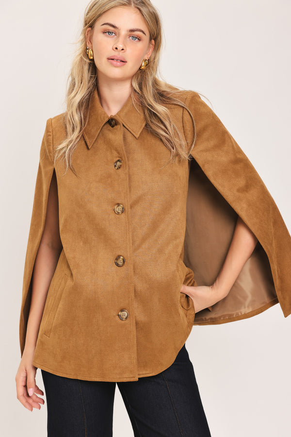 Woman wearing a camel suede capelet jacket with a collar, buttons, and matching  waist belt | Flying Tomato