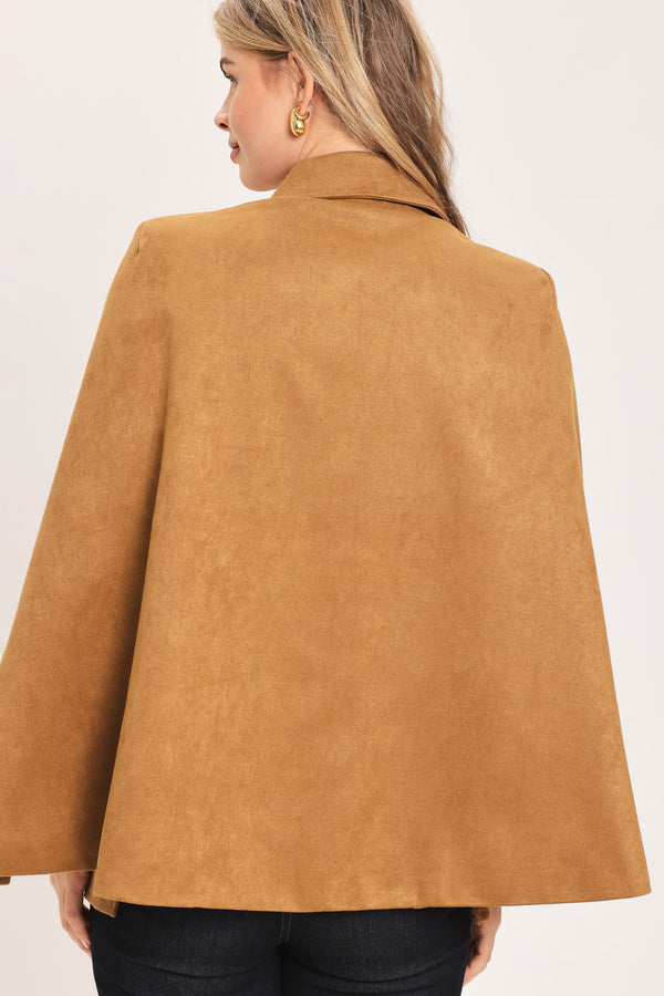 Woman wearing a camel suede capelet jacket with a collar, buttons, and matching  waist belt | Flying Tomato