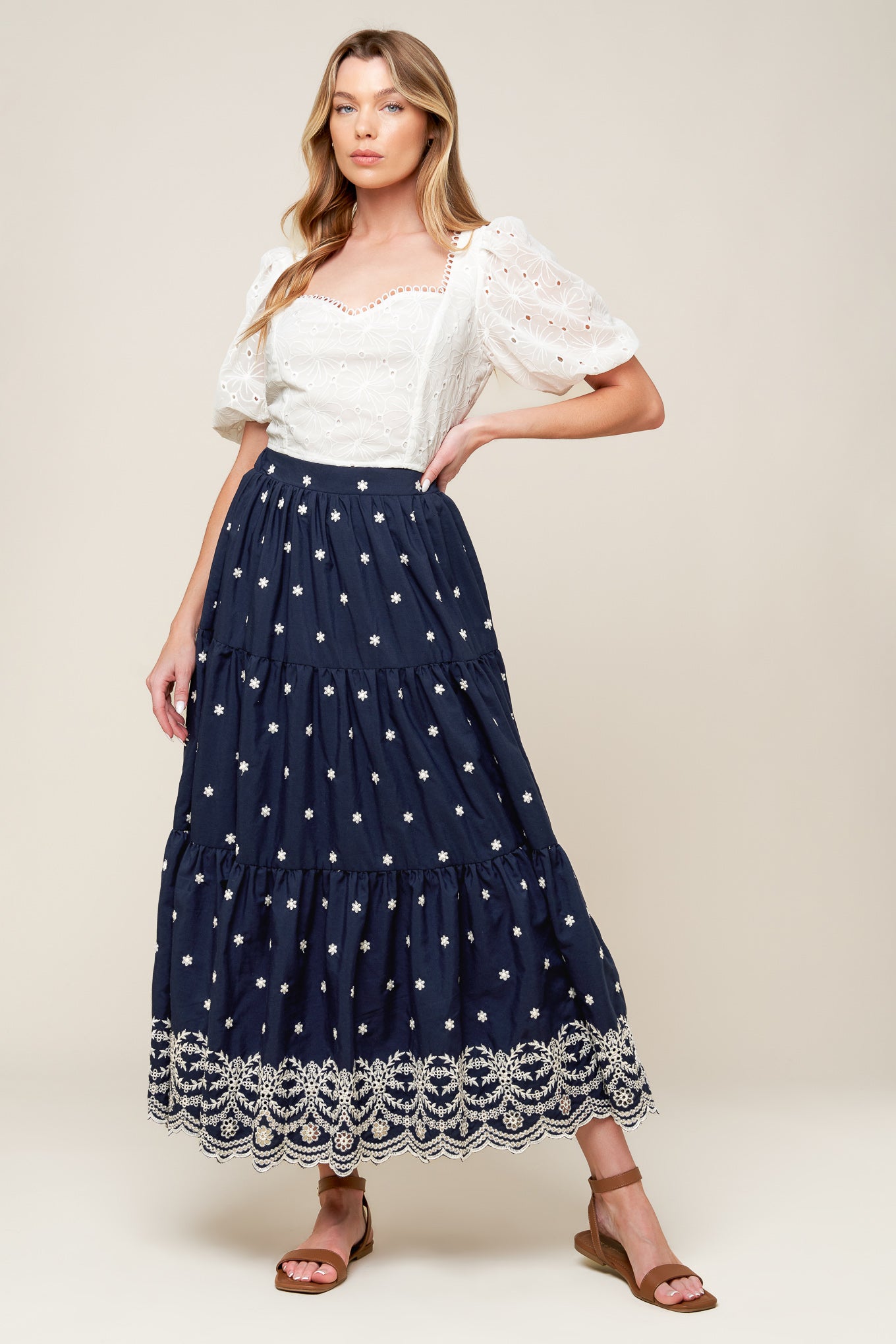 A solid navy embroidered woven midi skirt featuring tiered and elasticized back waistband.