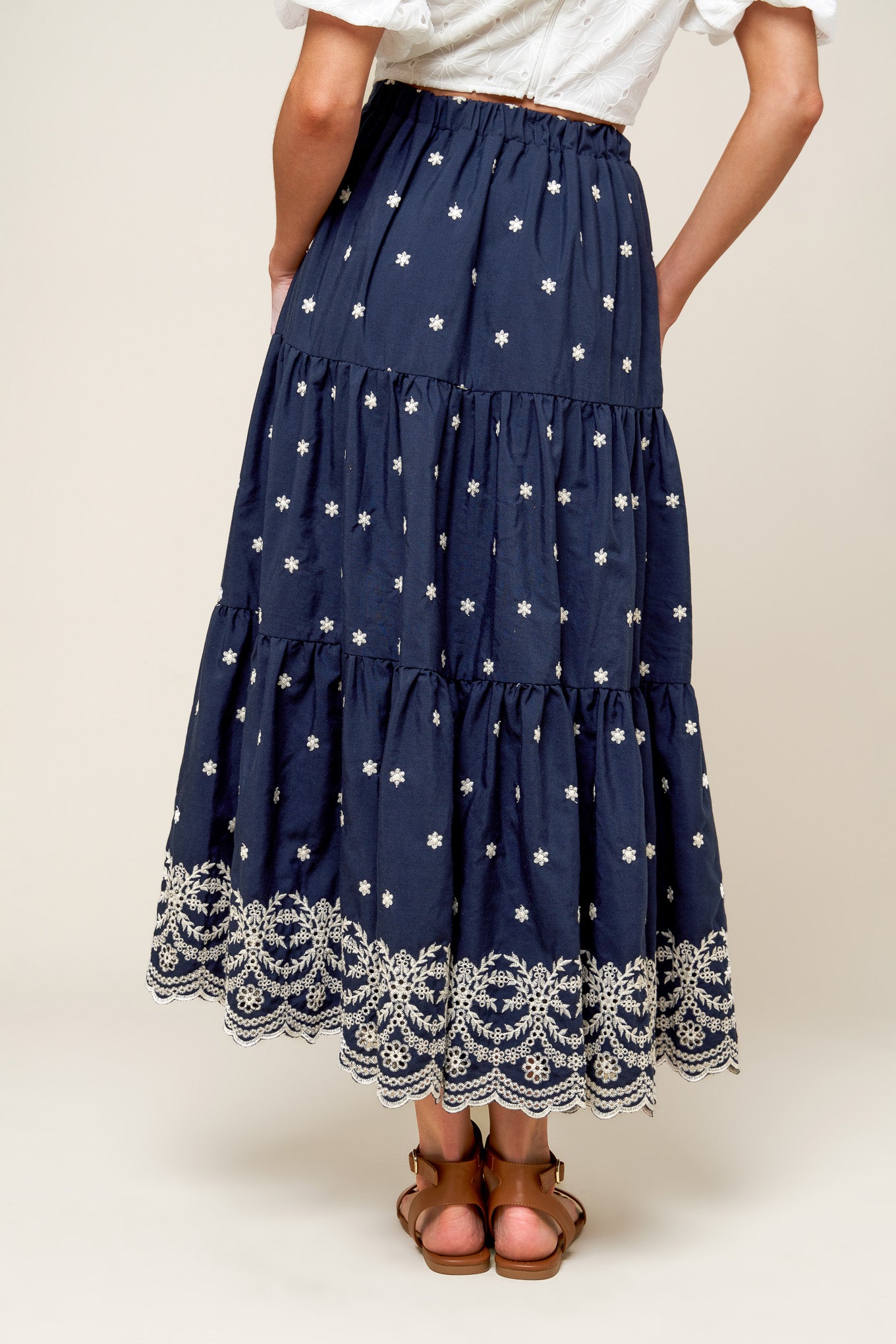 A solid navy embroidered woven midi skirt featuring tiered and elasticized back waistband.