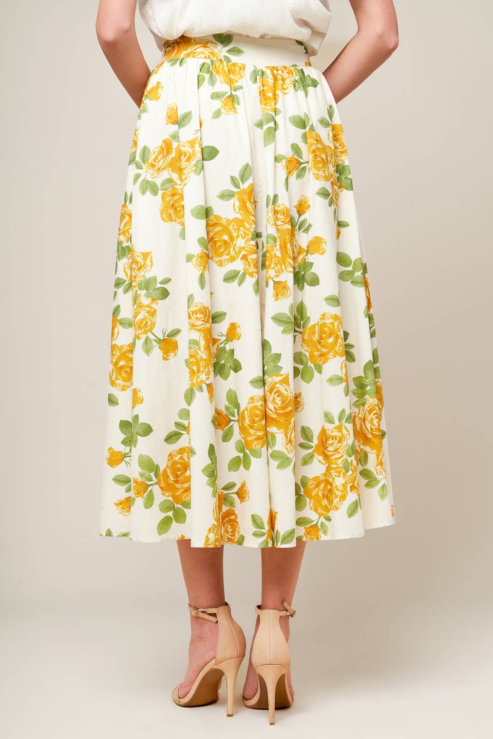 A cream woven full skirt featuring yellow floral print, side zipper closure and pockets.