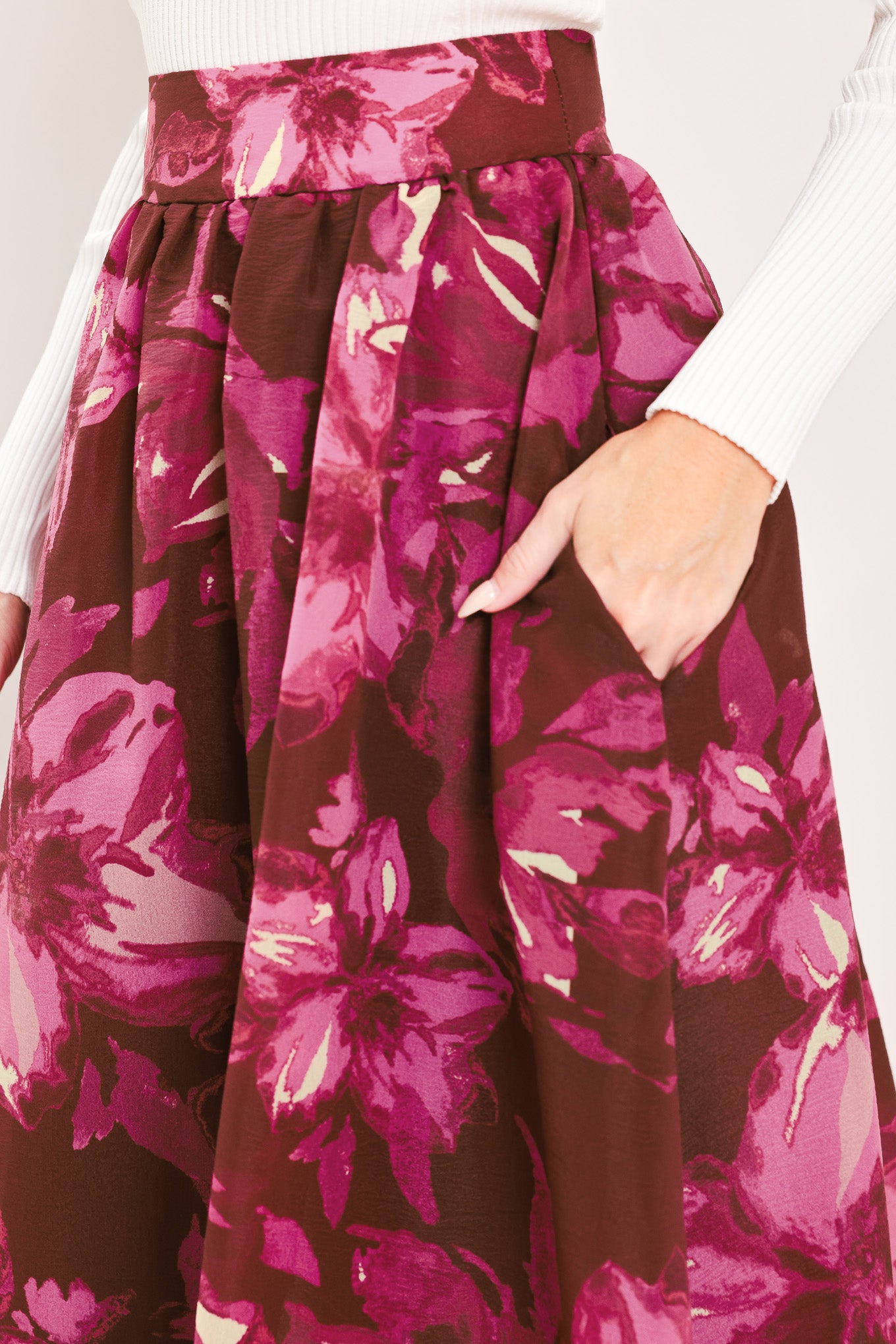 A model wearing a high-waisted, floor-length maxi A-line skirt with a dark burgundy base and a vibrant magenta floral pattern | Flying Tomato