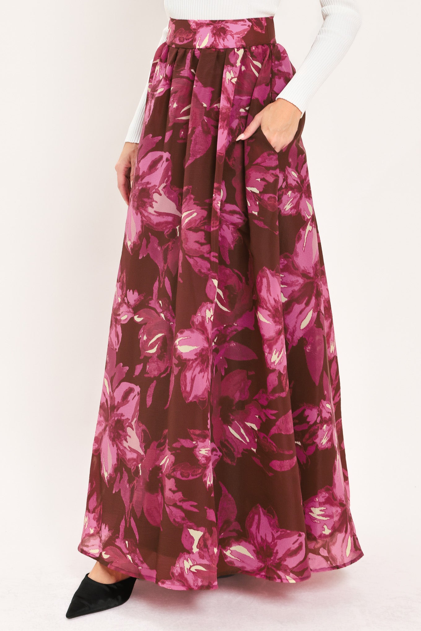 A model wearing a high-waisted, floor-length maxi A-line skirt with a dark burgundy base and a vibrant magenta floral pattern | Flying Tomato