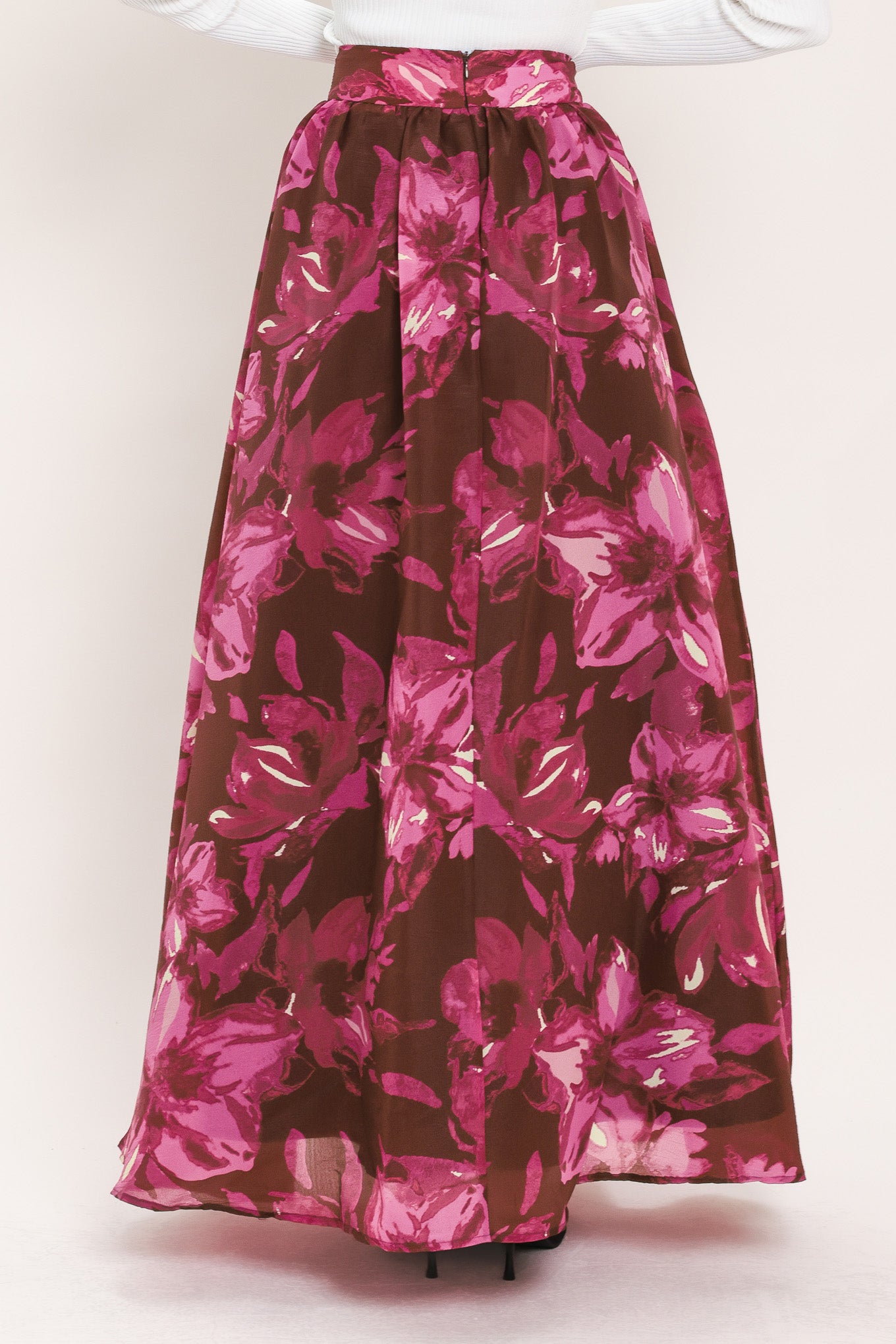 A model wearing a high-waisted, floor-length maxi A-line skirt with a dark burgundy base and a vibrant magenta floral pattern | Flying Tomato
