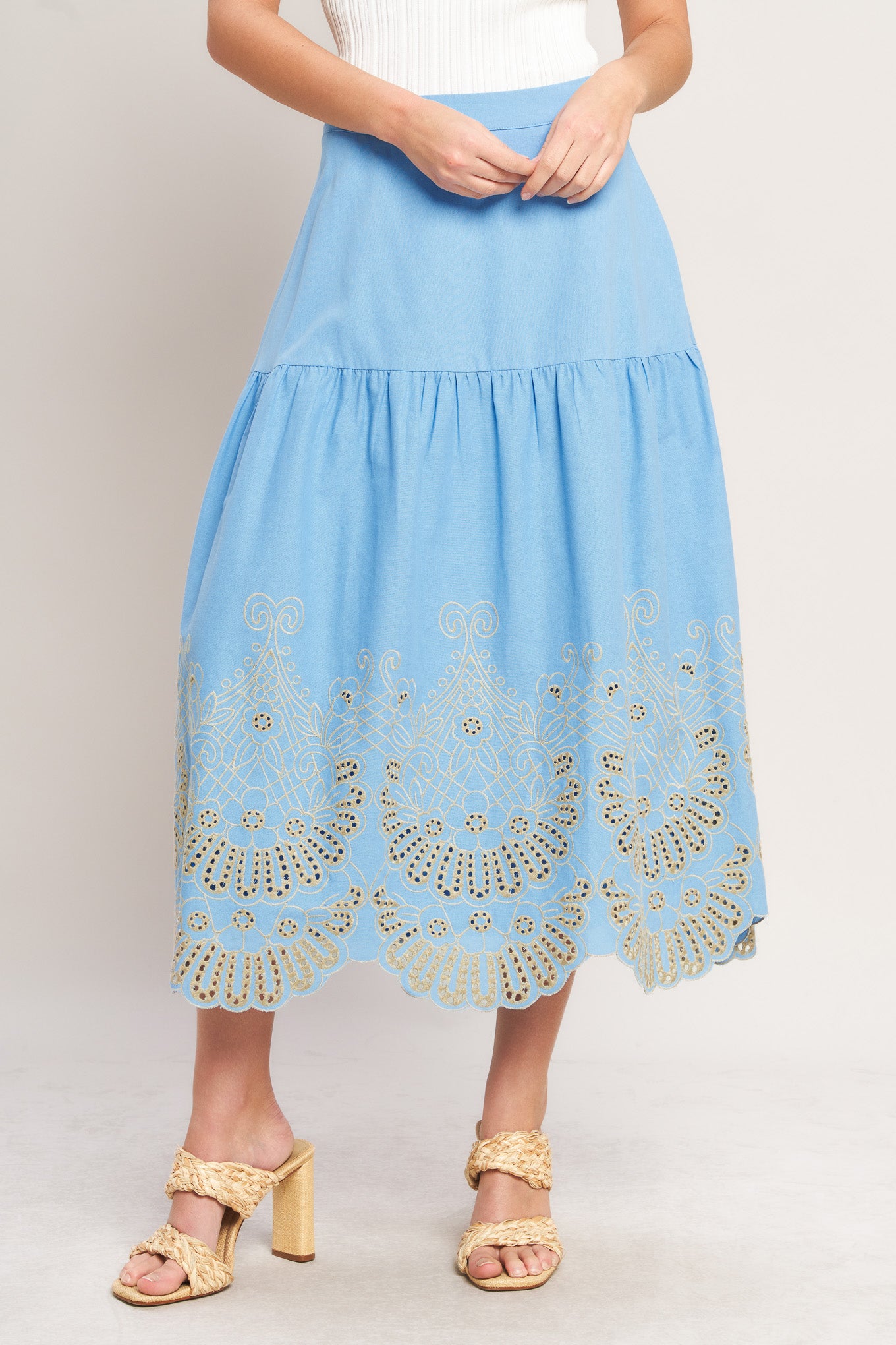 Light blue skirt with gold embroidery worn by a person on a plain background
