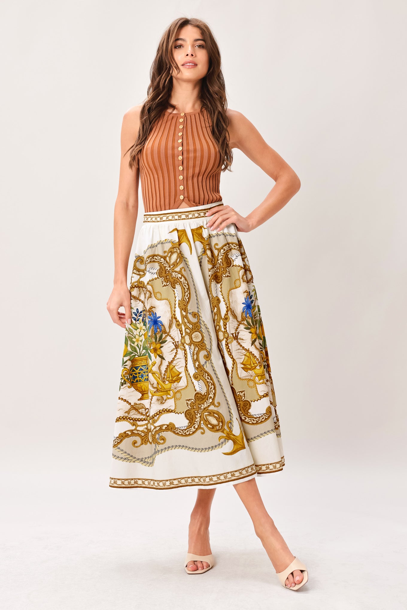 Woman wearing a midi skirt with intricate gold and multicolor pattern and side zipper closure | Flying Tomato
