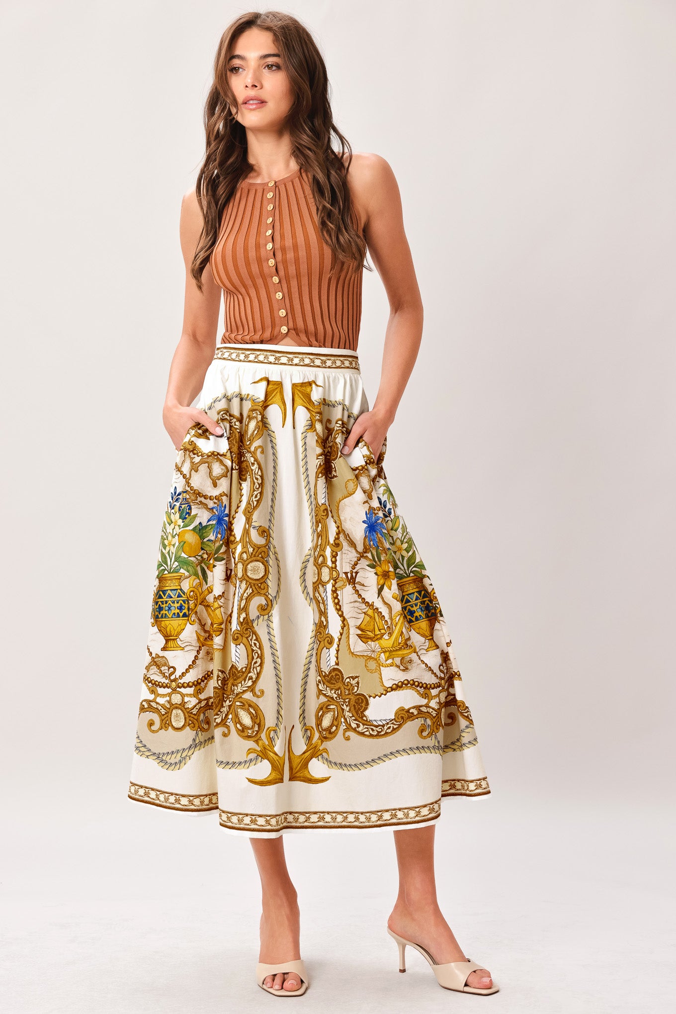 Woman wearing a midi skirt with intricate gold and multicolor pattern and side zipper closure | Flying Tomato