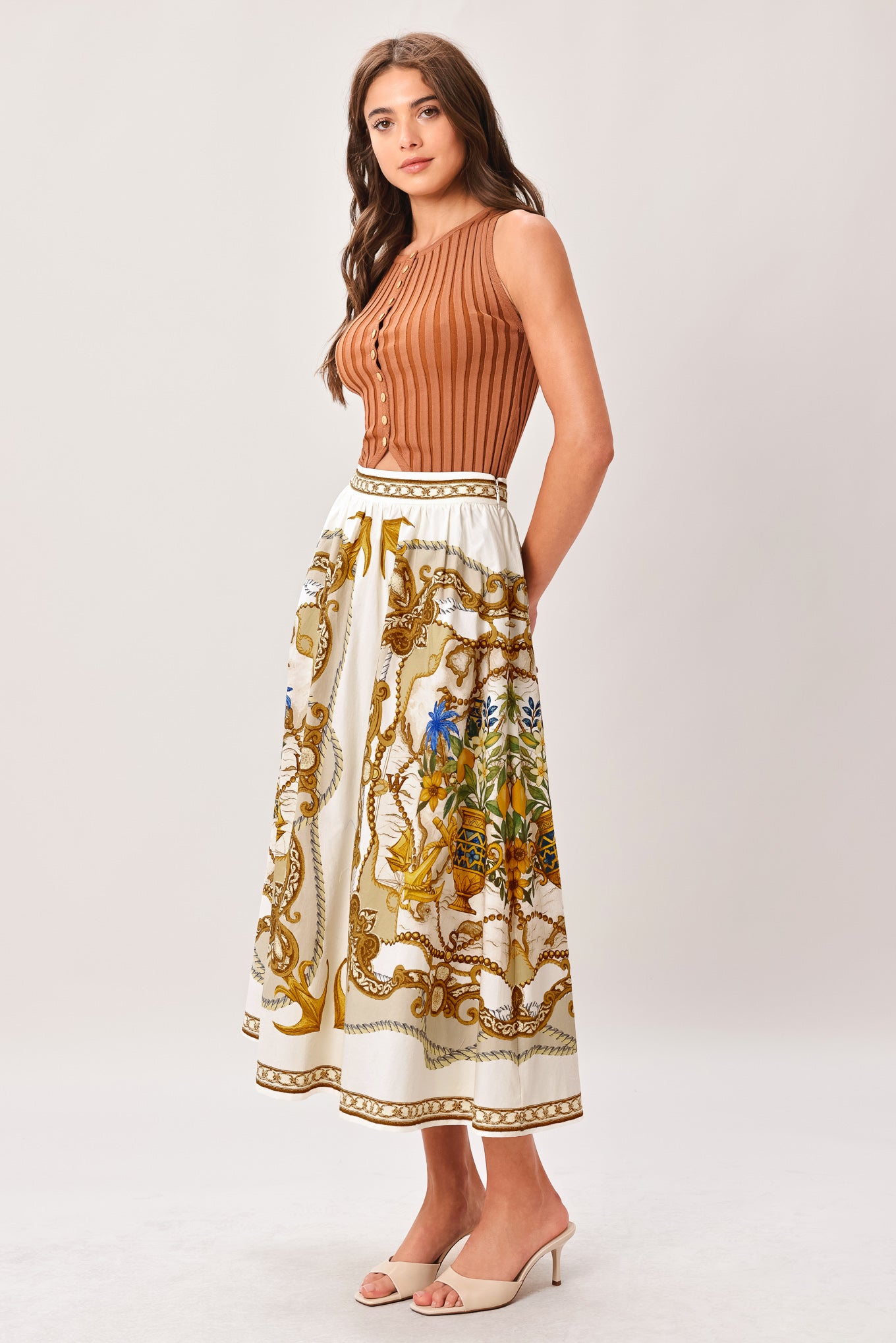 Woman wearing a midi skirt with intricate gold and multicolor pattern and side zipper closure | Flying Tomato