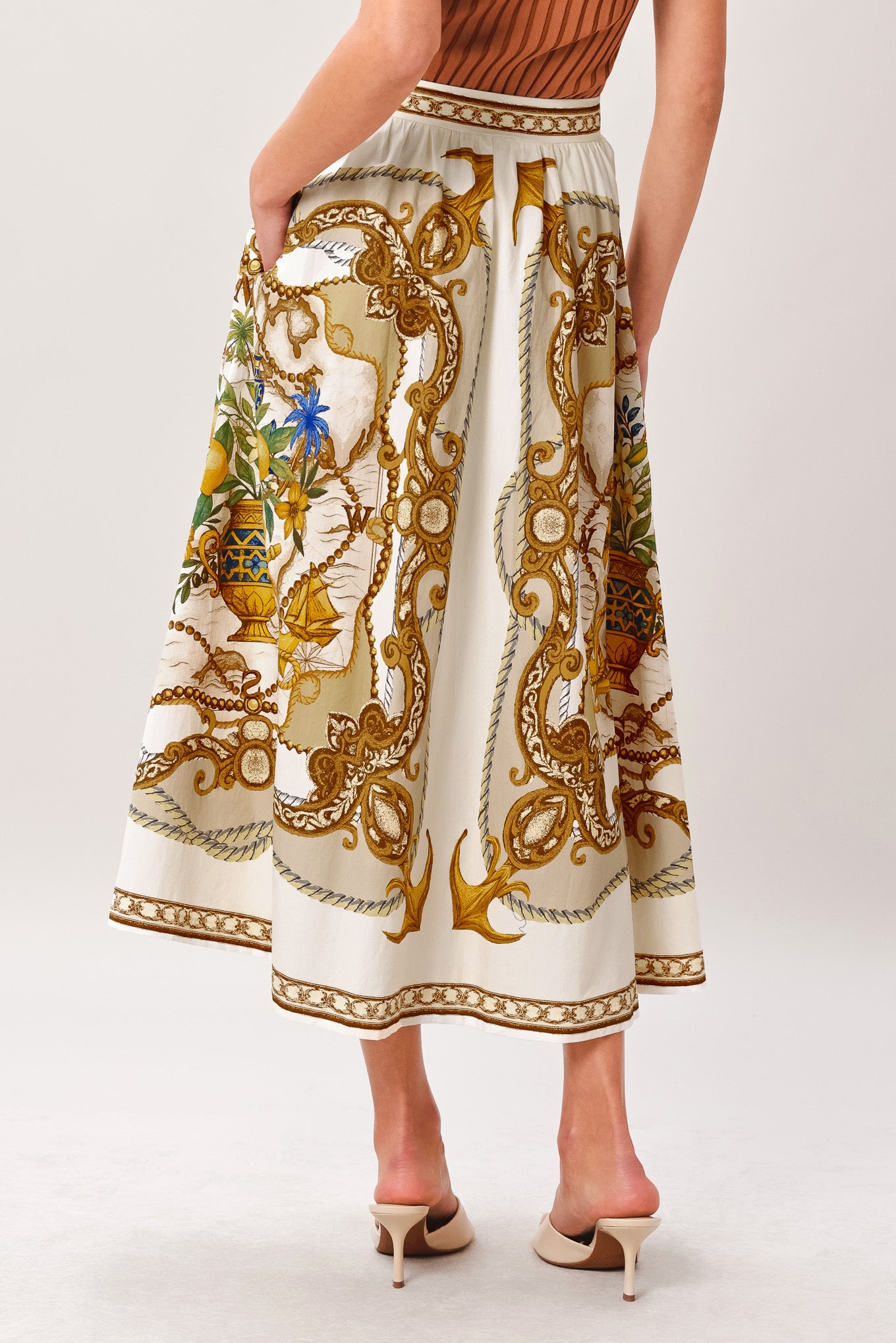 Woman wearing a midi skirt with intricate gold and multicolor pattern and side zipper closure | Flying Tomato