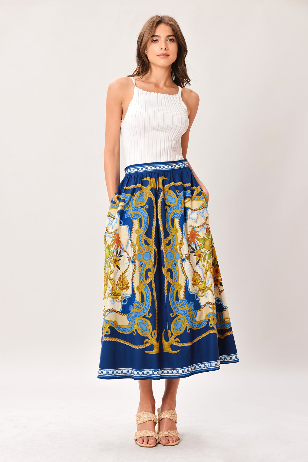 Woman wearing a midi skirt with intricate blue, gold and multicolor pattern and side zipper closure | Flying Tomato