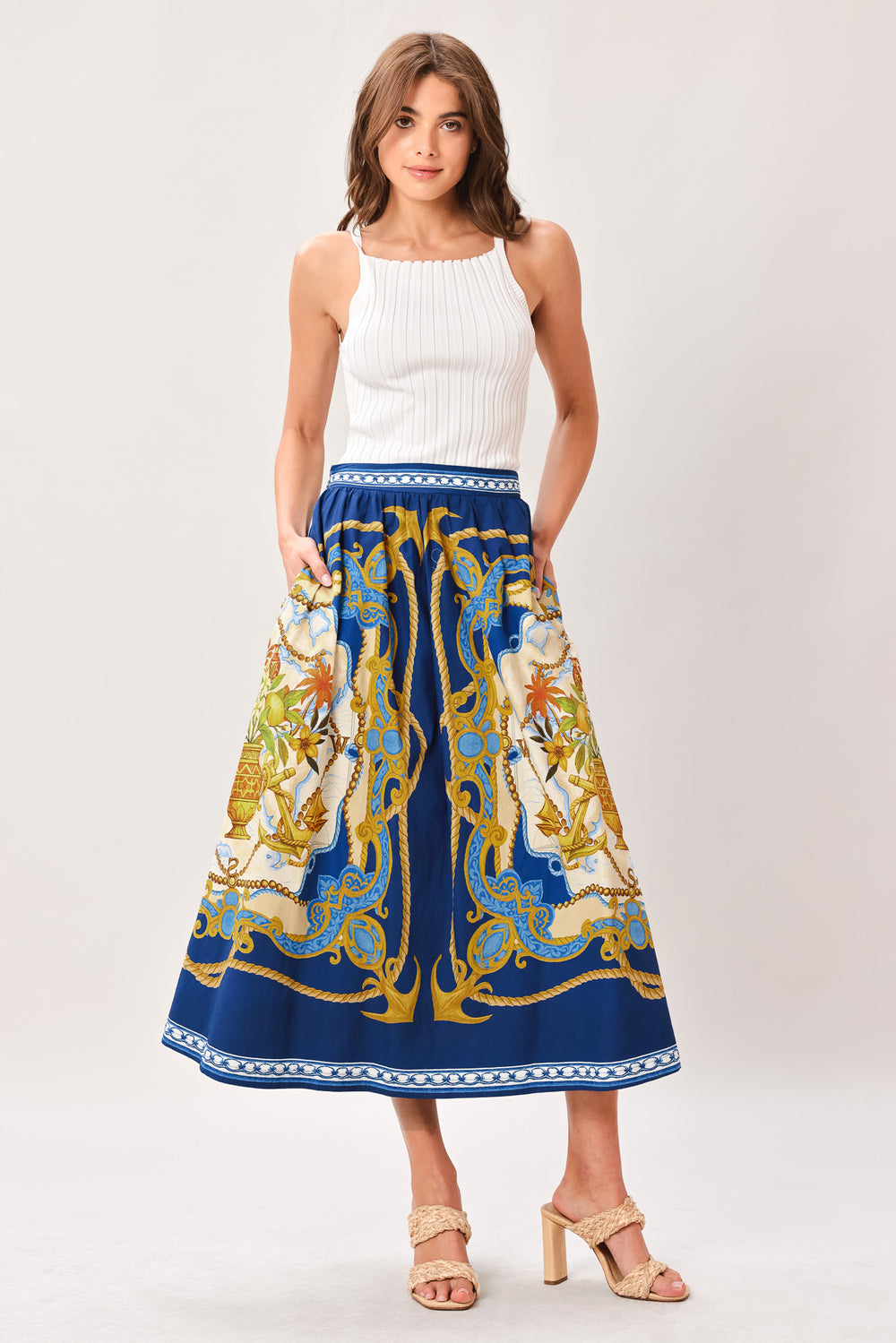 Woman wearing a midi skirt with intricate blue, gold and multicolor pattern and side zipper closure | Flying Tomato