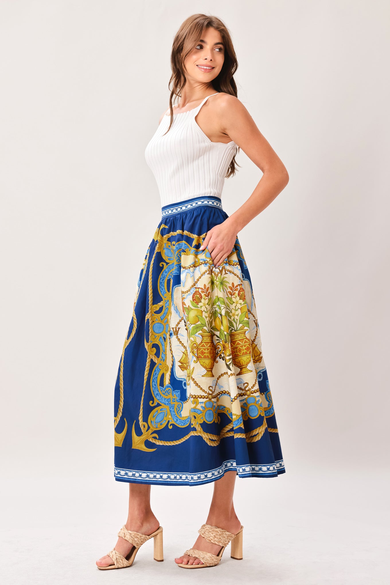 Woman wearing a midi skirt with intricate blue, gold and multicolor pattern and side zipper closure | Flying Tomato