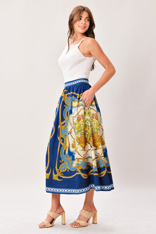 Woman wearing a midi skirt with intricate blue, gold and multicolor pattern and side zipper closure | Flying Tomato