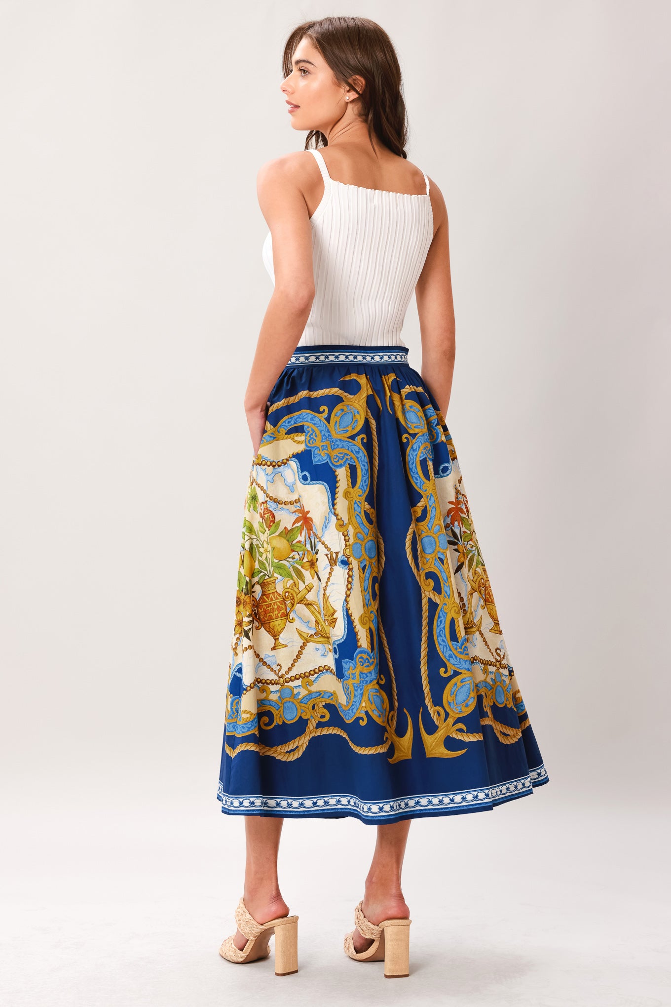Woman wearing a midi skirt with intricate blue, gold and multicolor pattern and side zipper closure | Flying Tomato