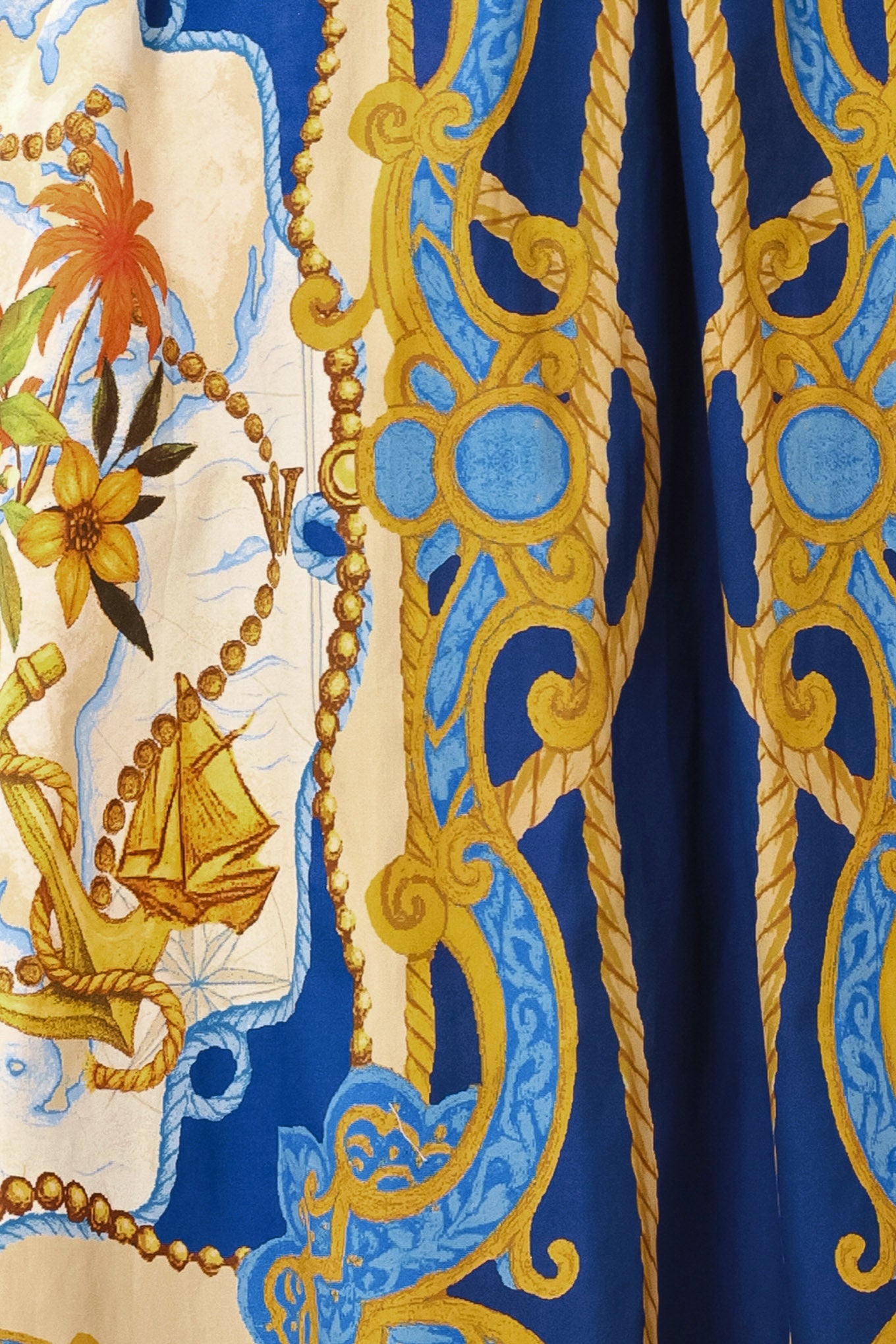Close-up of a patterned fabric with blue, gold, and beige design | Flying Tomato