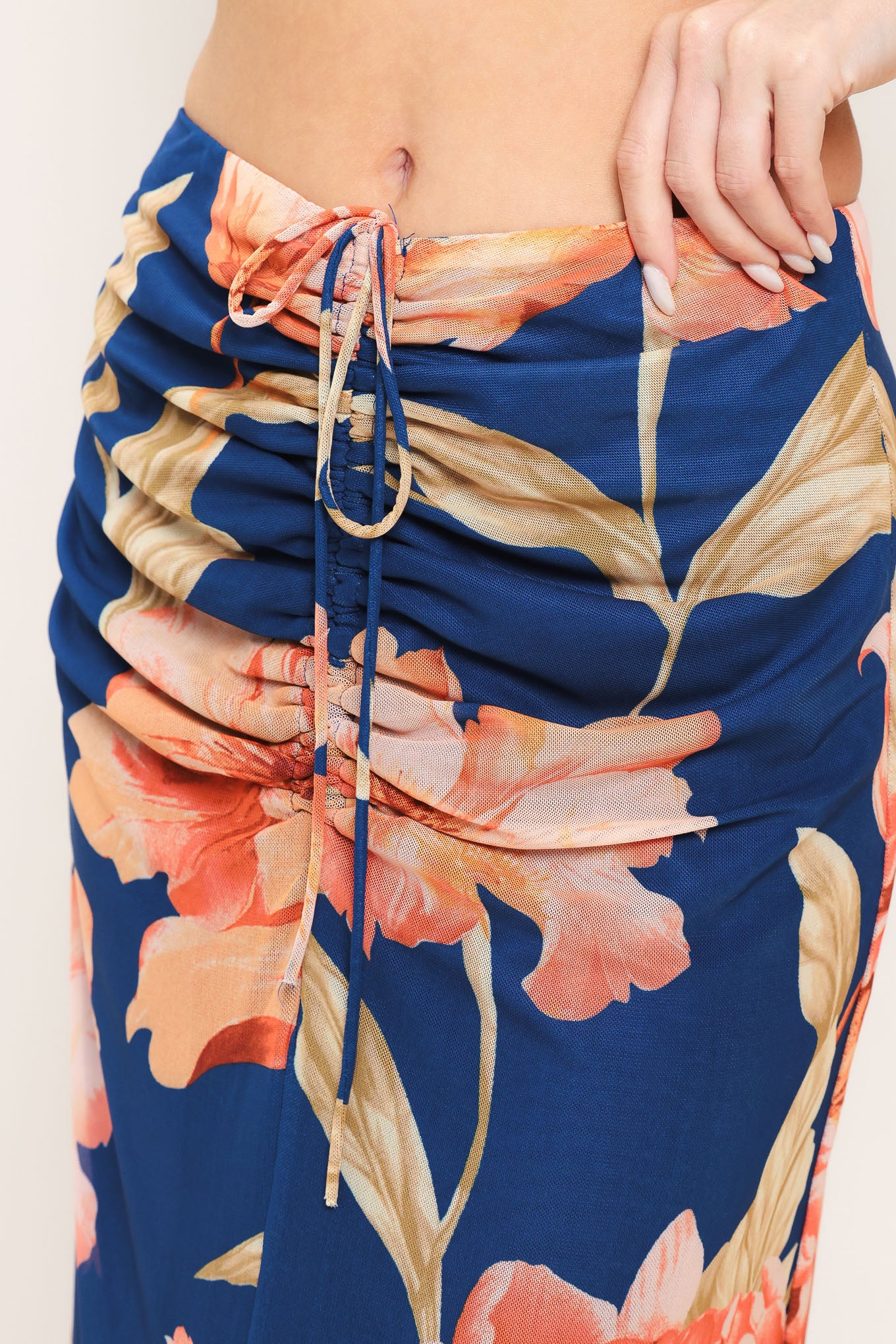 Woman wearing a navy blue with coral flowers power mesh midi skirt with front center shirring with tie and back zipper closure | Flying Tomato