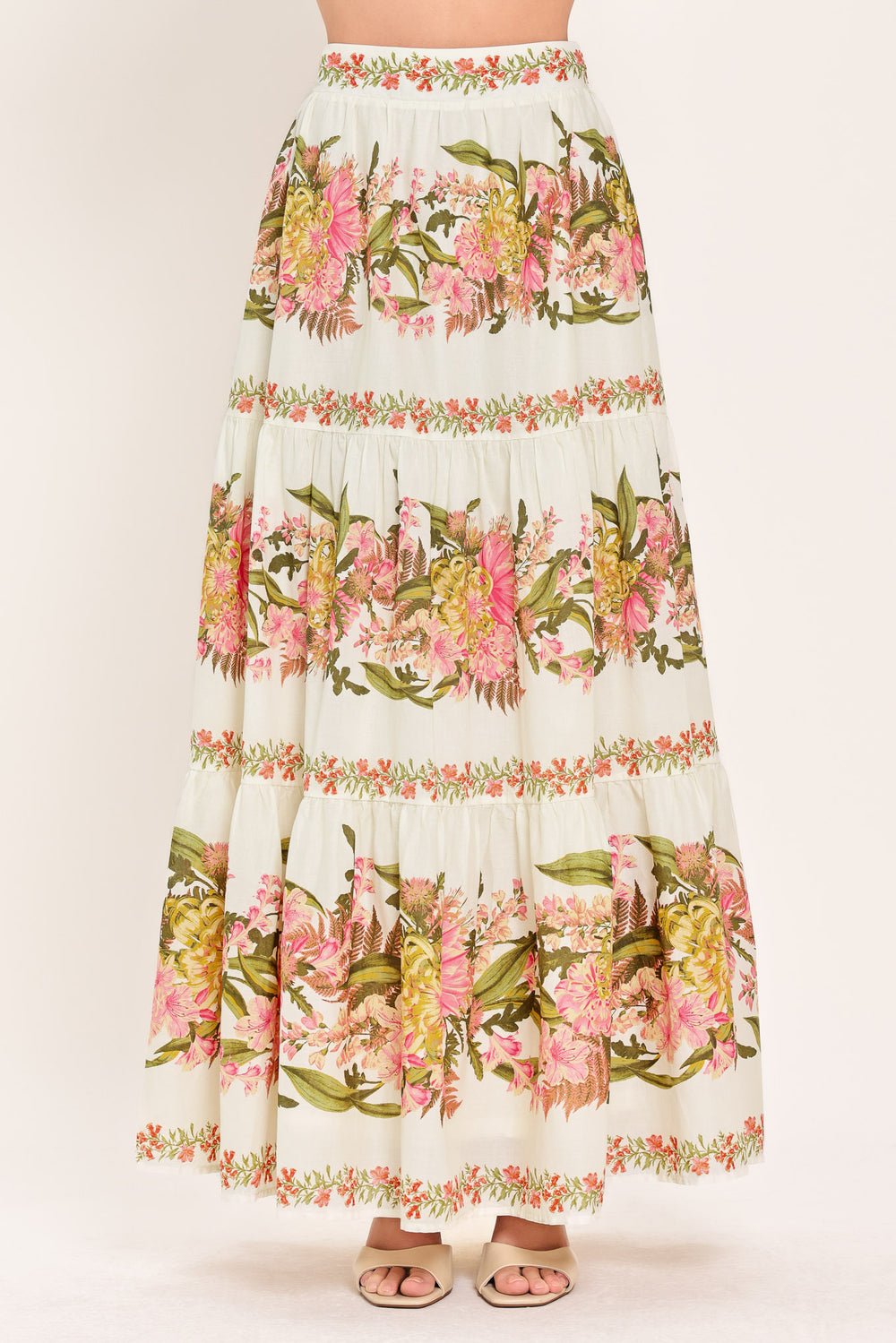 Woman wearing a pink, green and white floral print woven maxi skirt with tiers and smocked back waistband | Flying Tomato