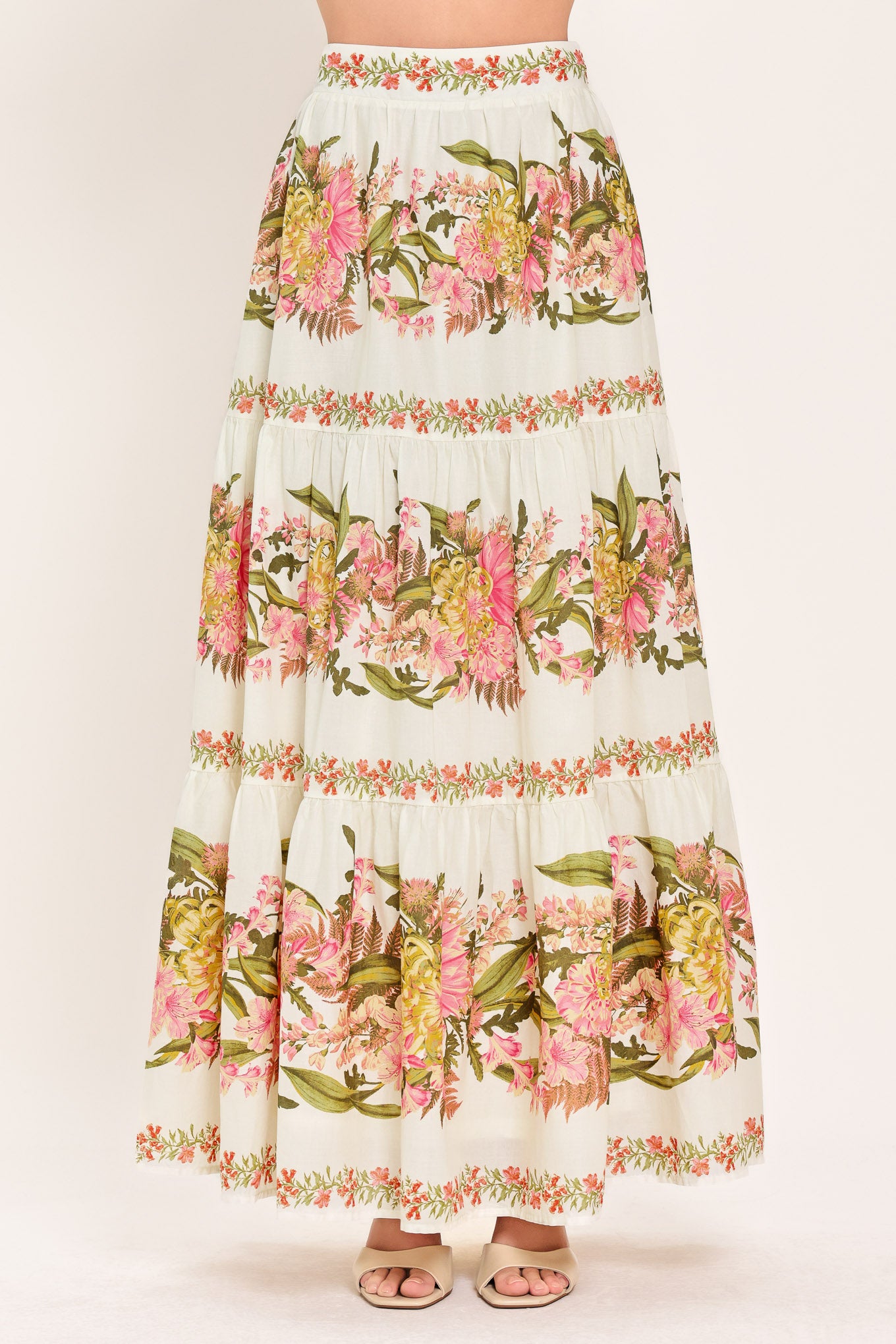 Woman wearing a pink, green and white floral print woven maxi skirt with tiers and smocked back waistband | Flying Tomato