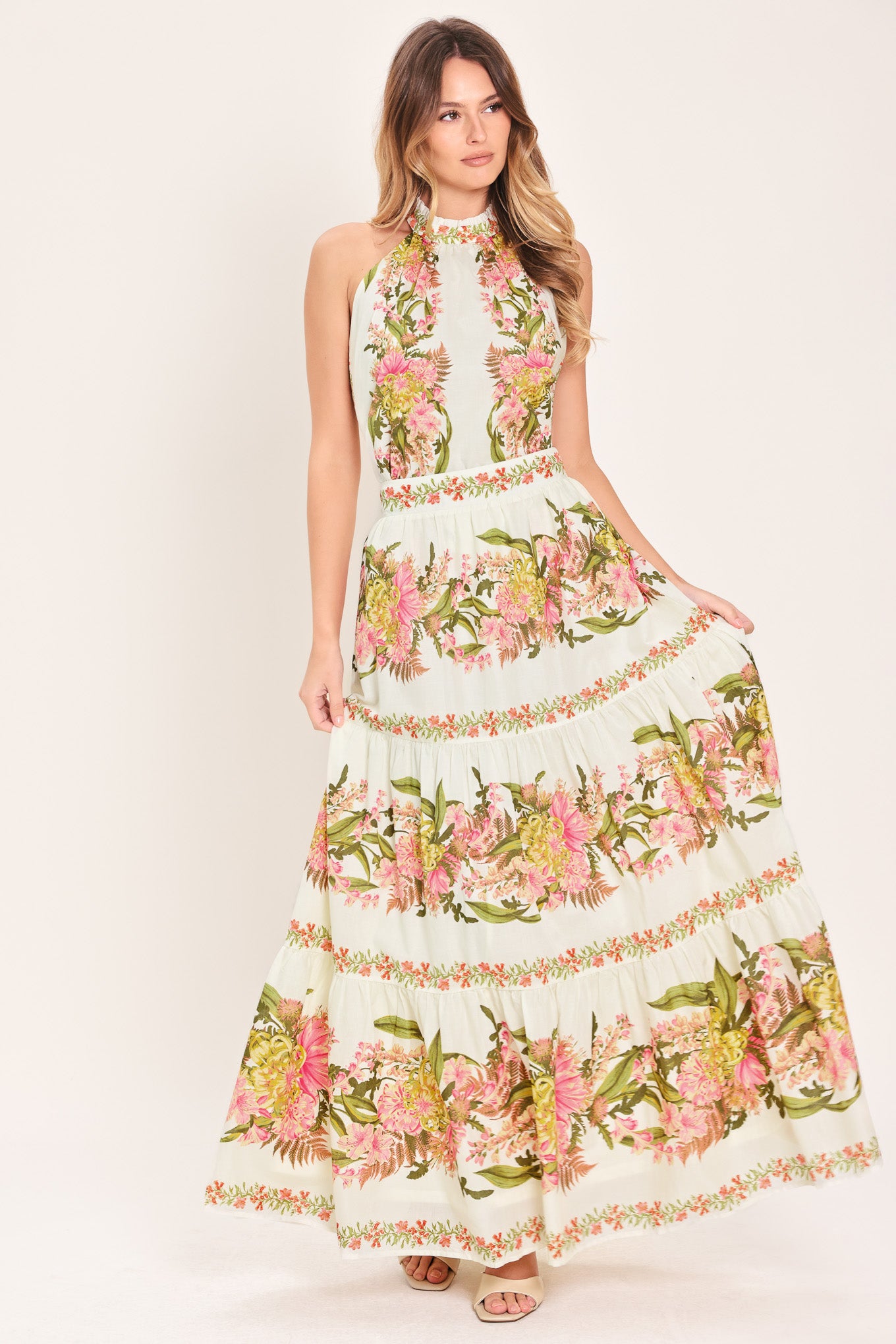Woman wearing a pink, green and white floral print woven maxi skirt with tiers and smocked back waistband | Flying Tomato