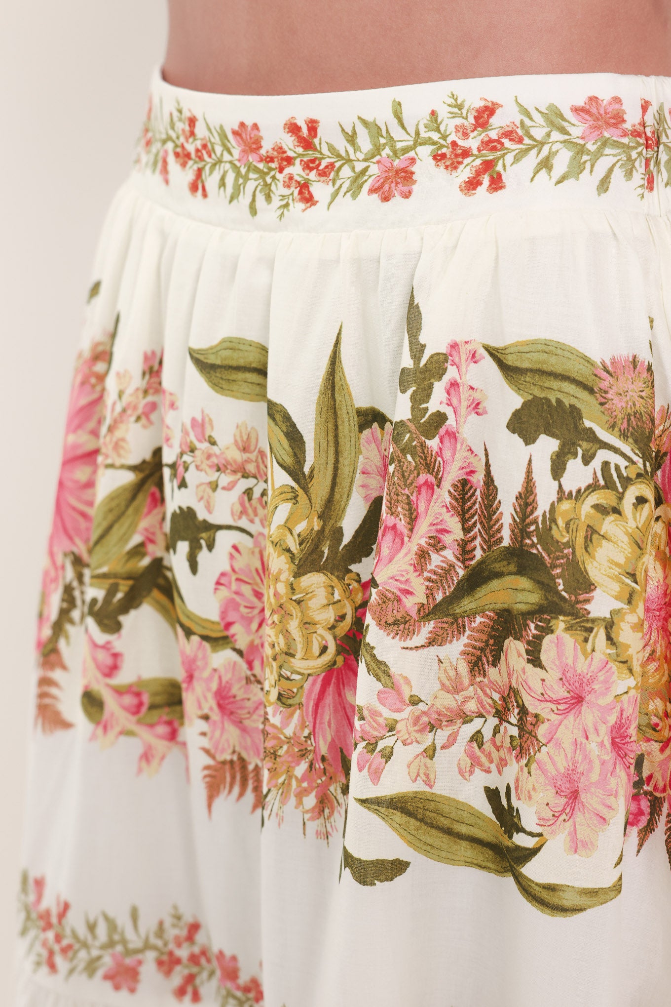 Woman wearing a pink, green and white floral print woven maxi skirt with tiers and smocked back waistband | Flying Tomato