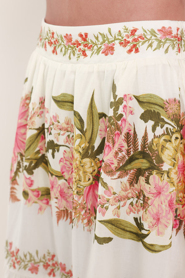 Woman wearing a pink, green and white floral print woven maxi skirt with tiers and smocked back waistband | Flying Tomato