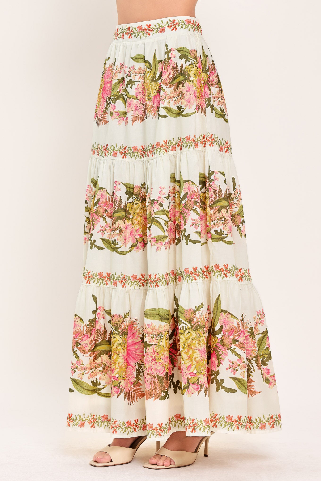 Woman wearing a pink, green and white floral print woven maxi skirt with tiers and smocked back waistband | Flying Tomato
