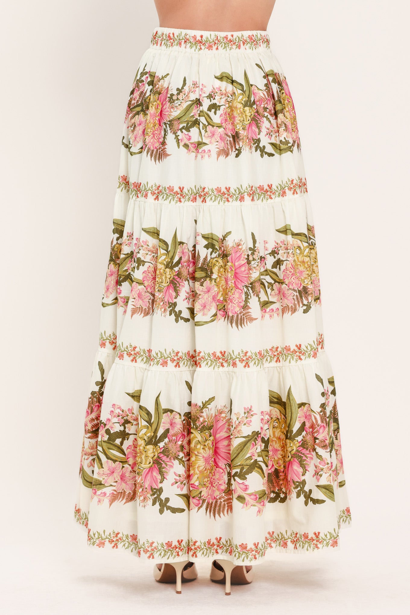 Woman wearing a pink, green and white floral print woven maxi skirt with tiers and smocked back waistband | Flying Tomato