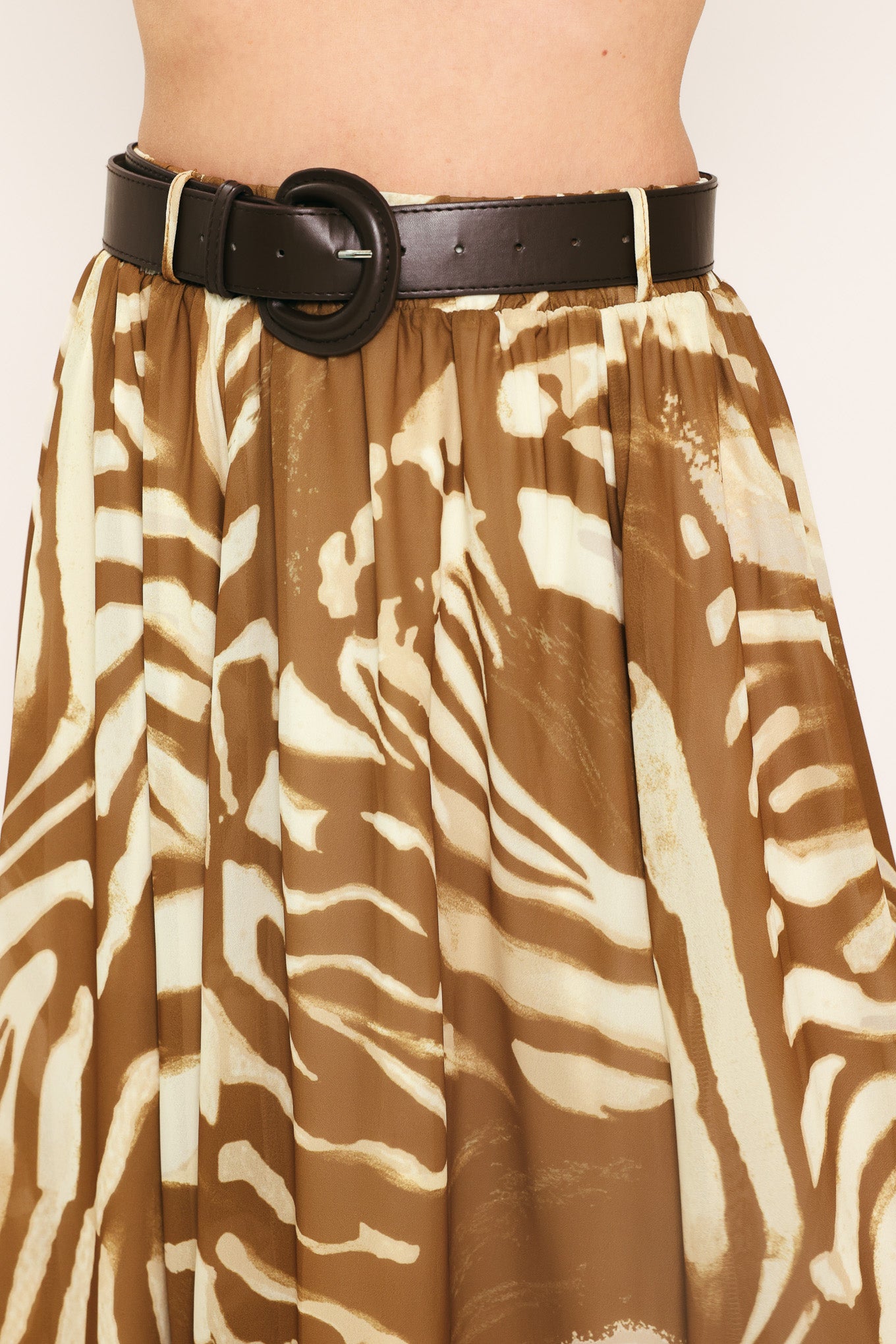 Woman wearing a mocha and taupe zebra print midi skirt with a belt | Flying Tomato