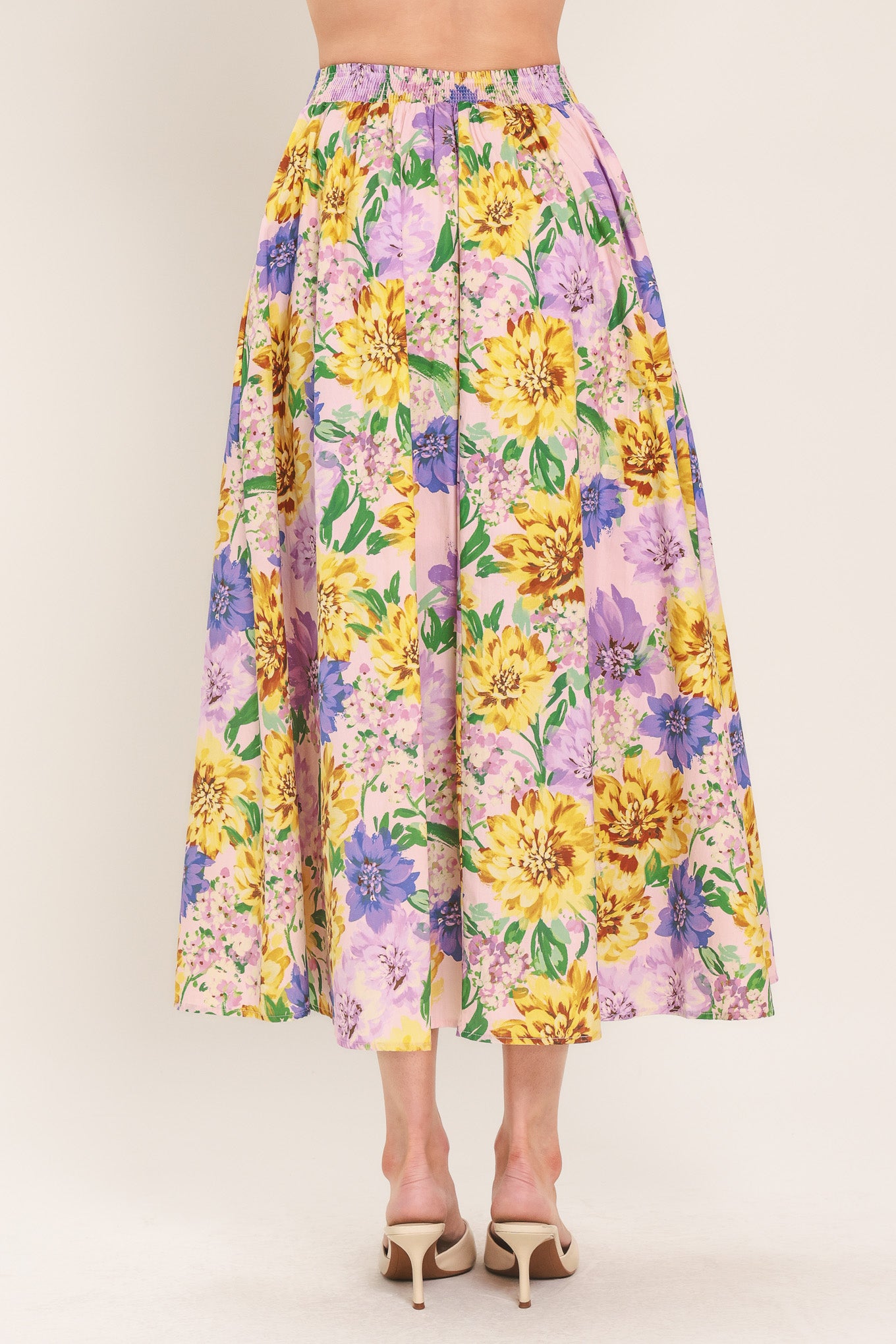 Woman wearing a yellow and purple floral patterned full midi skirt with front button detail and smocked back waistband | Flying Tomato