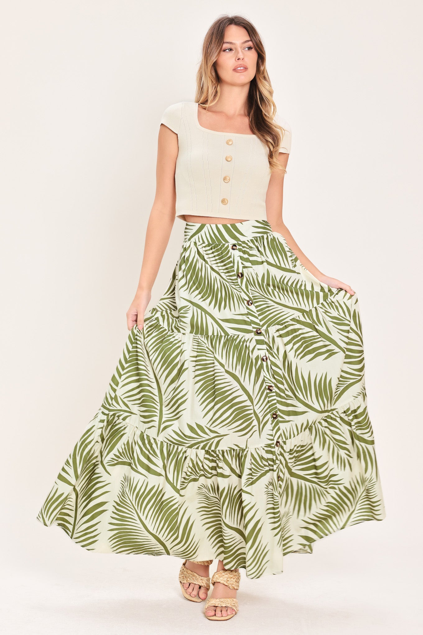 Woman wearing a green leaf-patterned maxi skirt featuring front button down, tiers and smocked back waistband | Flying Tomato