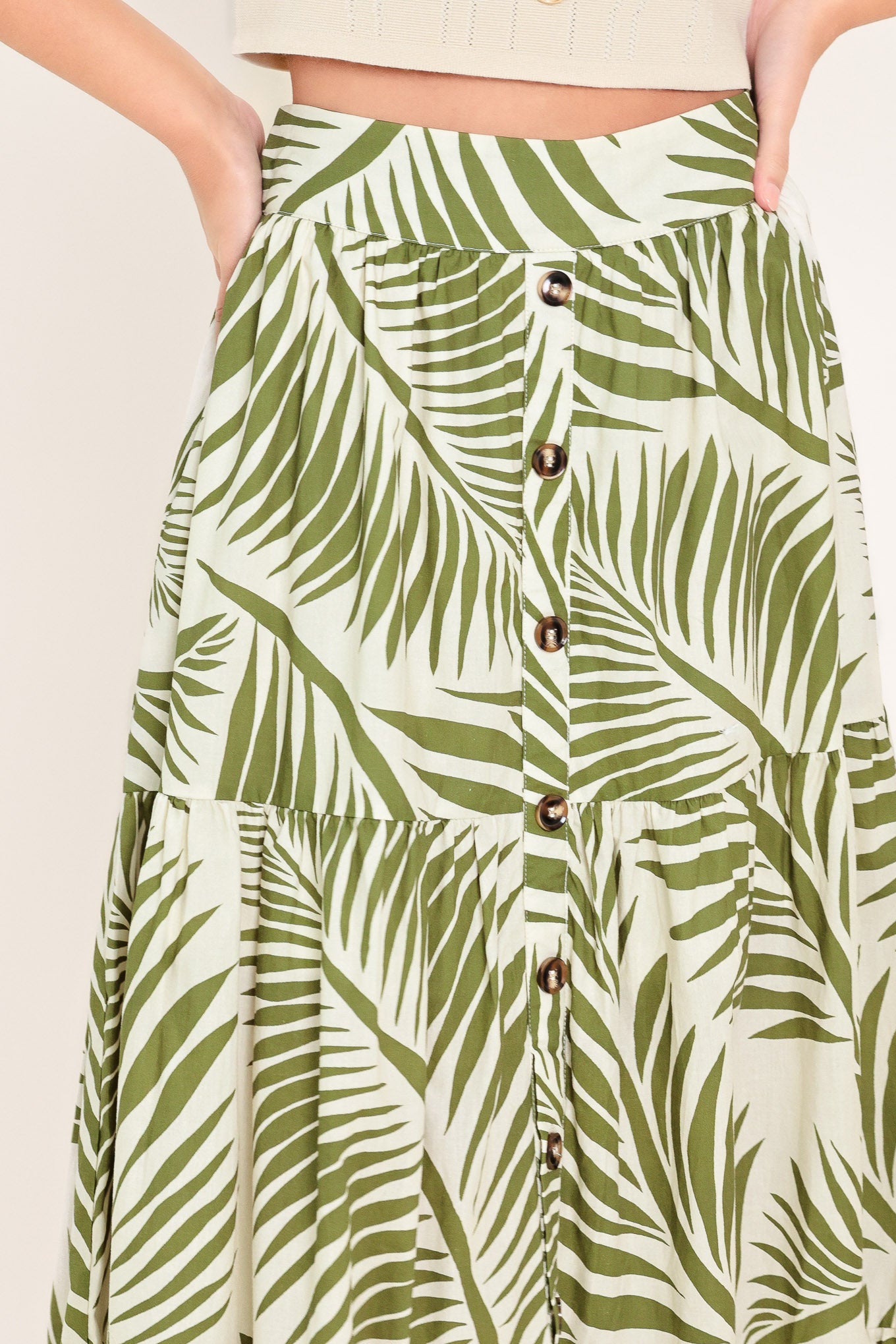 Woman wearing a green leaf-patterned maxi skirt featuring front button down, tiers and smocked back waistband | Flying Tomato