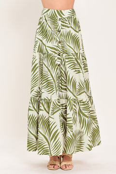 Woman wearing a green leaf-patterned maxi skirt featuring front button down, tiers and smocked back waistband | Flying Tomato