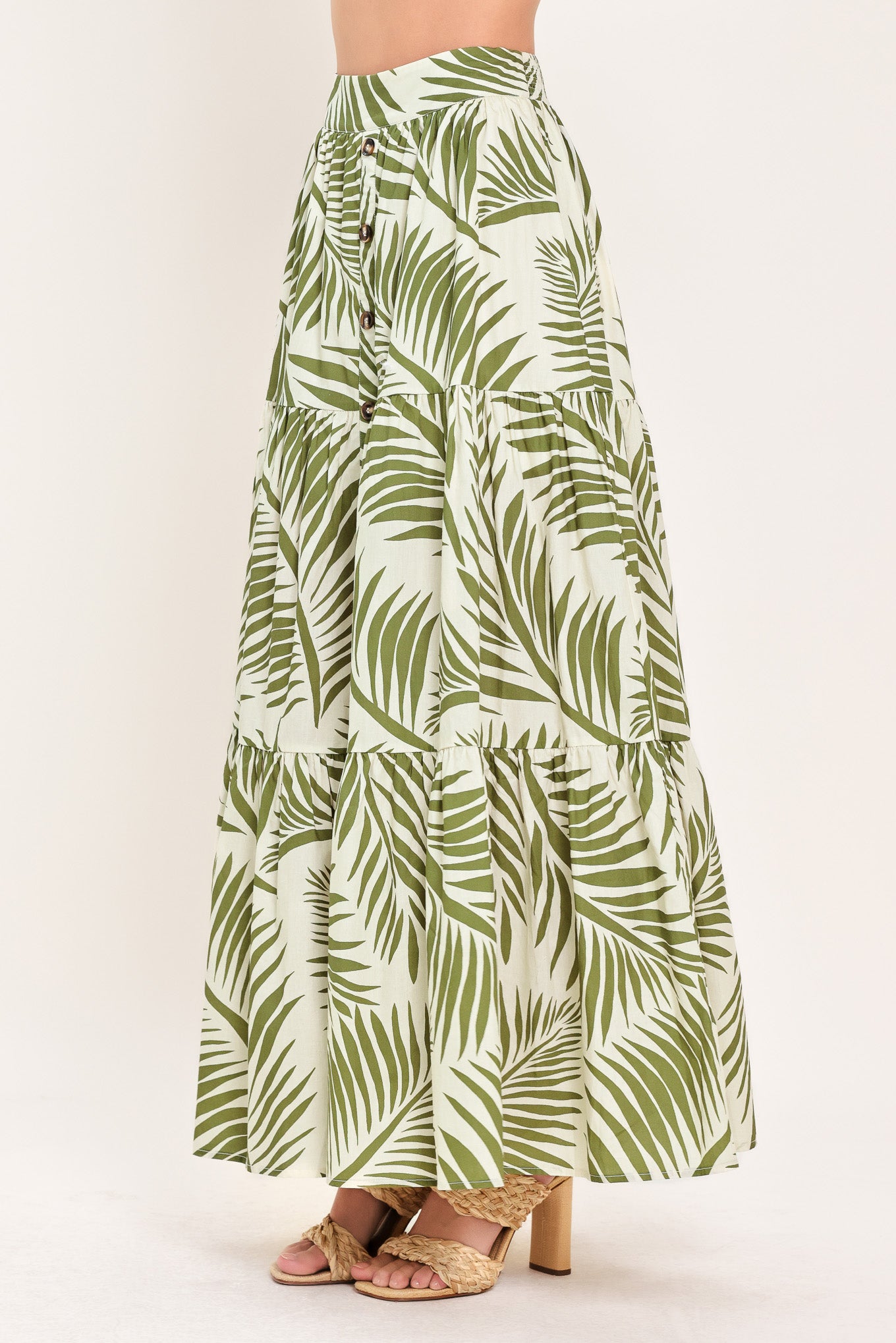 Woman wearing a green leaf-patterned maxi skirt featuring front button down, tiers and smocked back waistband | Flying Tomato