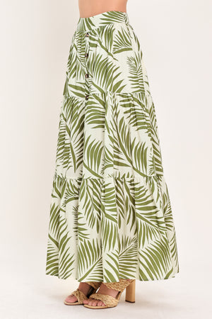 Woman wearing a green leaf-patterned maxi skirt featuring front button down, tiers and smocked back waistband | Flying Tomato