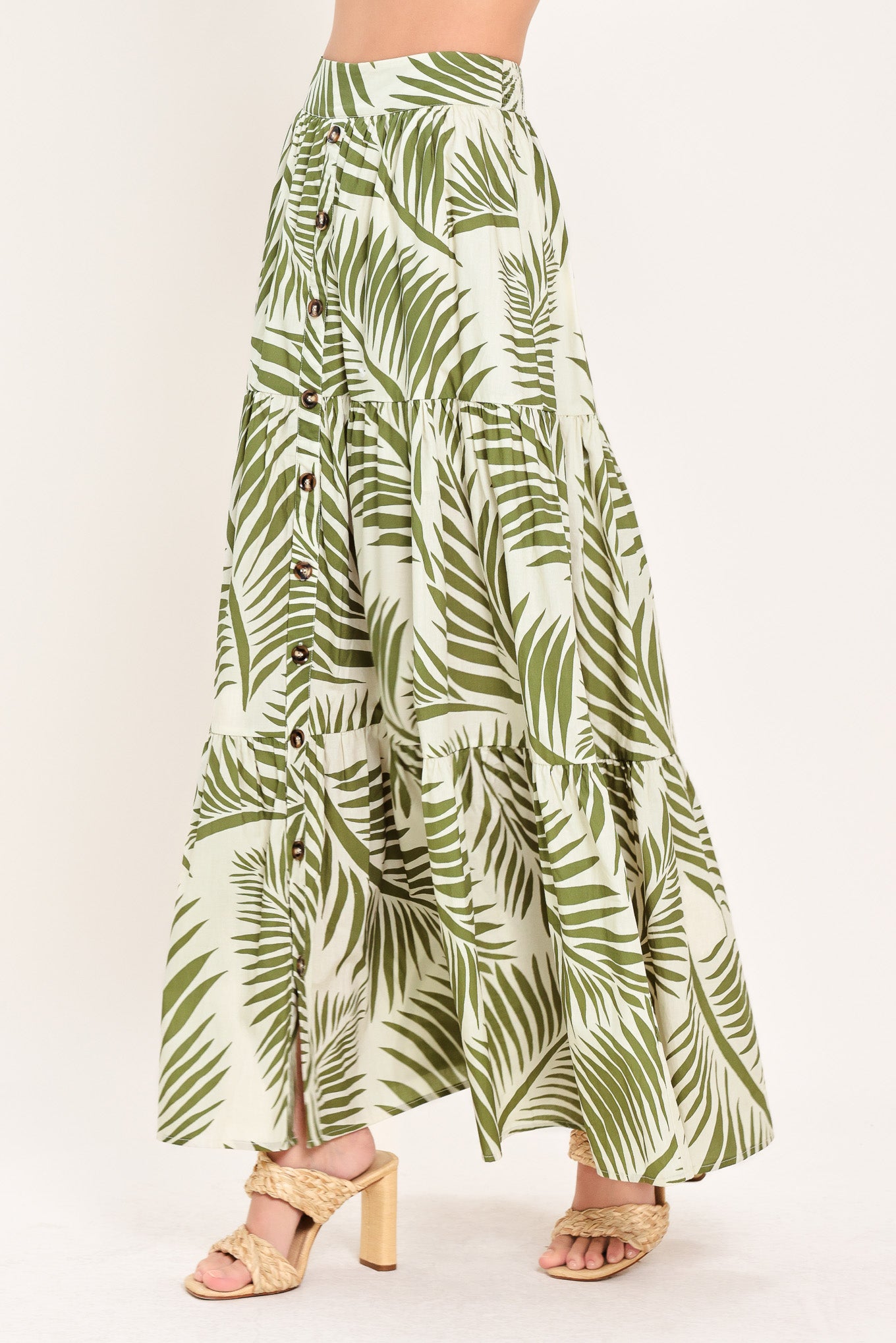 Woman wearing a green leaf-patterned maxi skirt featuring front button down, tiers and smocked back waistband | Flying Tomato