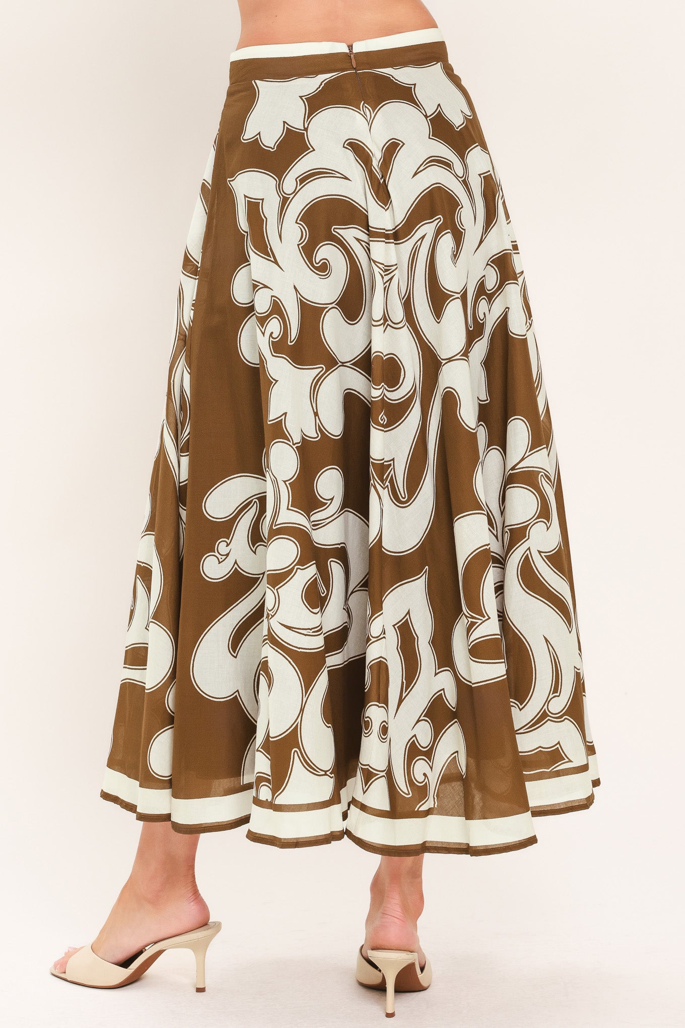 A woman wearing a brown midi skirt with a large white baroque pattern | Flying Tomato